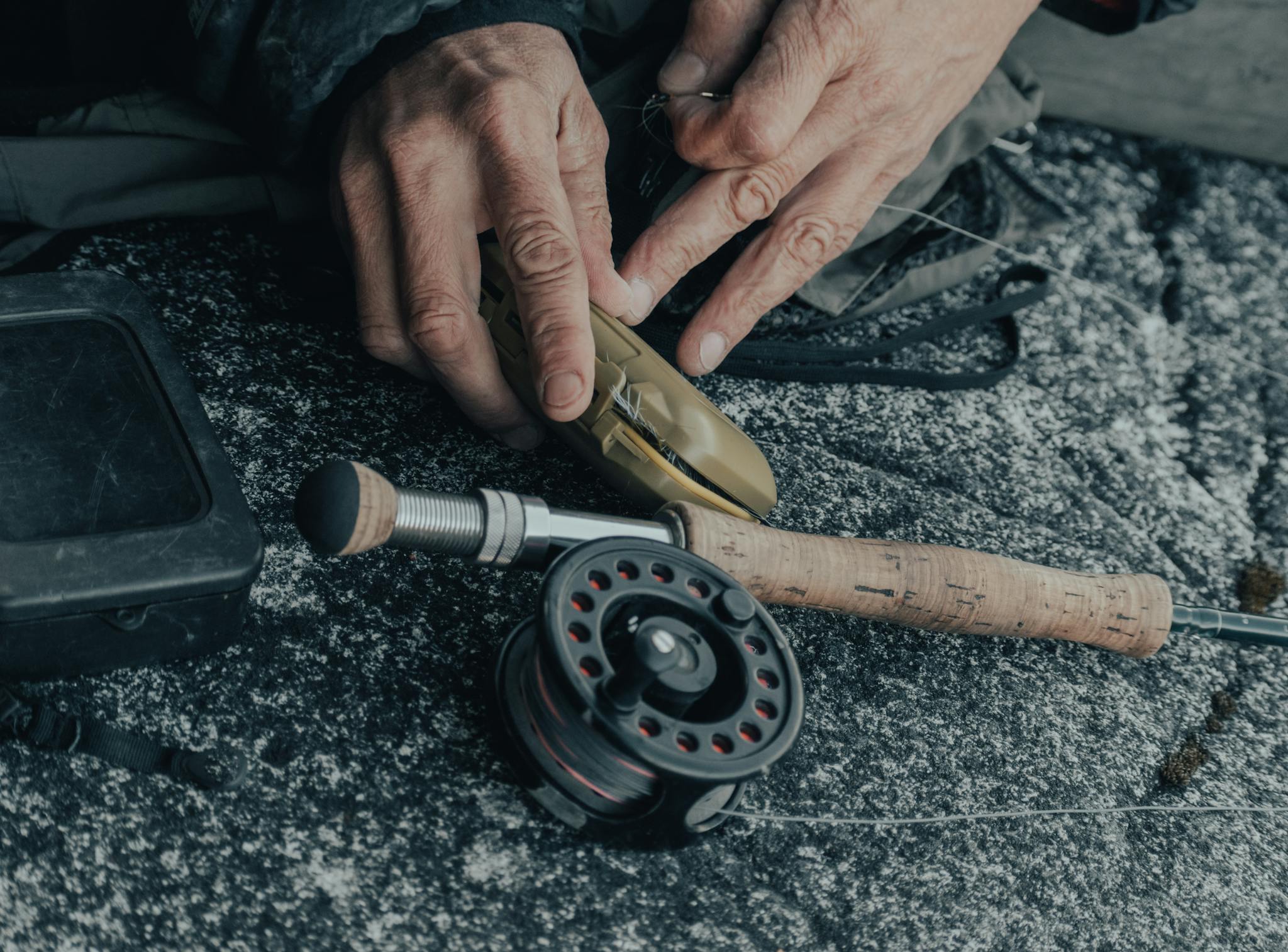 A Person Holding Brown Box Beside a Fishing Rod